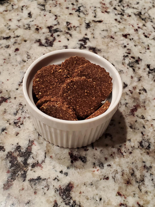 White ramekin with brown dog treats on a speckled countertop