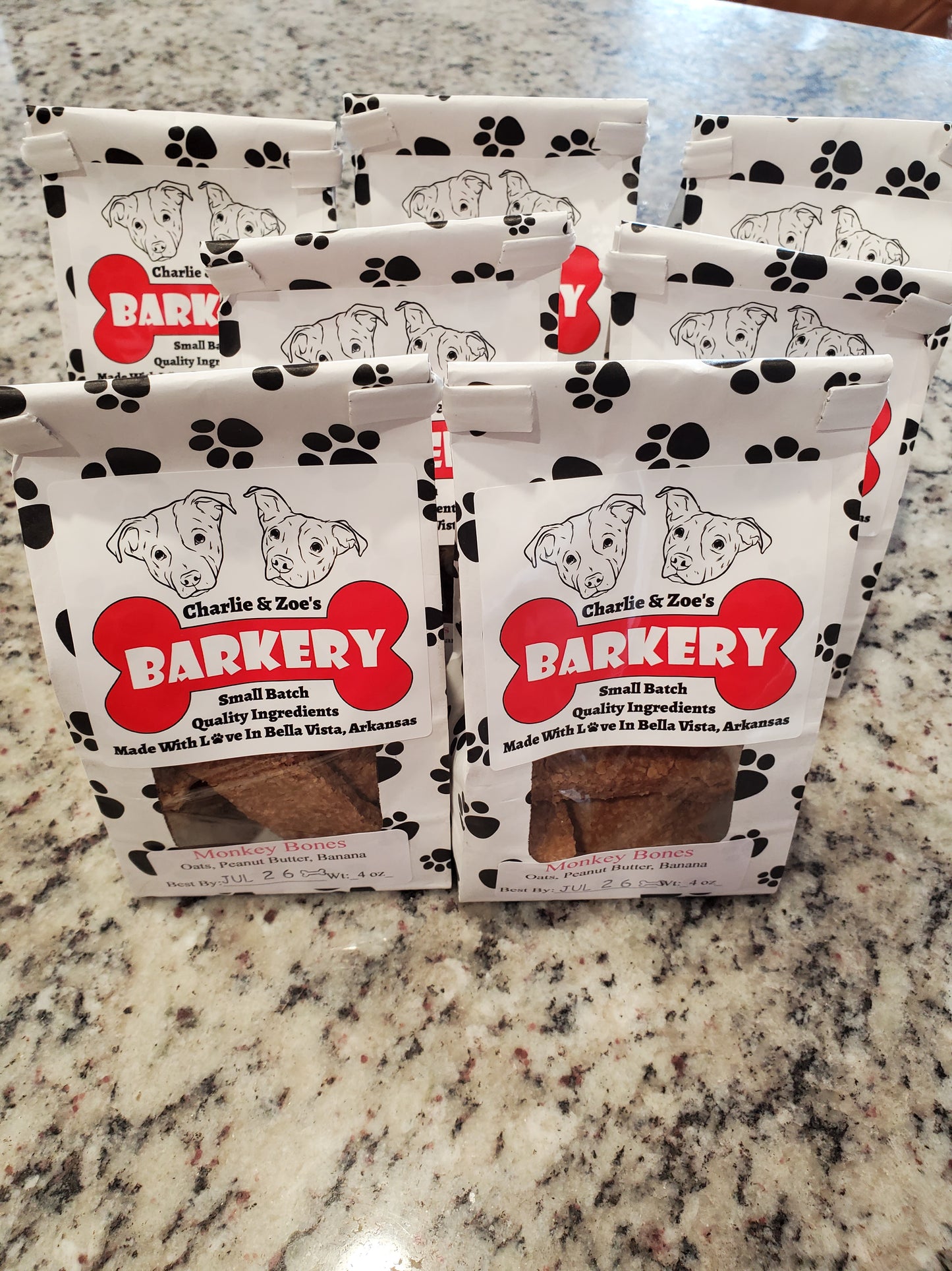 Four packages of Charlie & Zoe's Barkery dog treats on a granite countertop.
