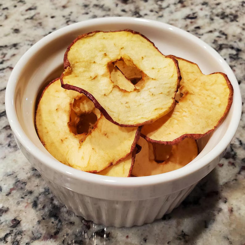 Dried apple slices in a white bowl on a marble countertop