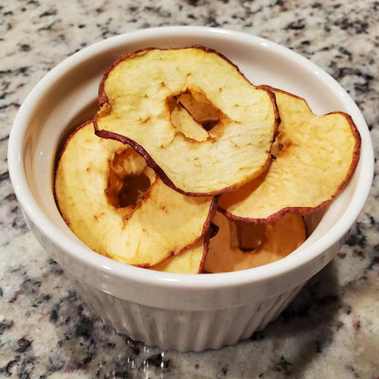 Dried apple slices in a white bowl on a marble countertop