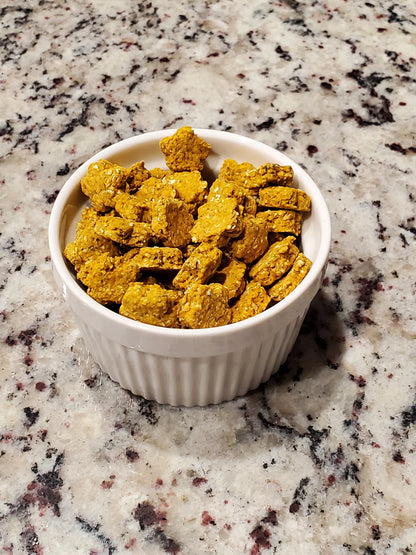 White bowl filled with yellow cat treats on a speckled countertop