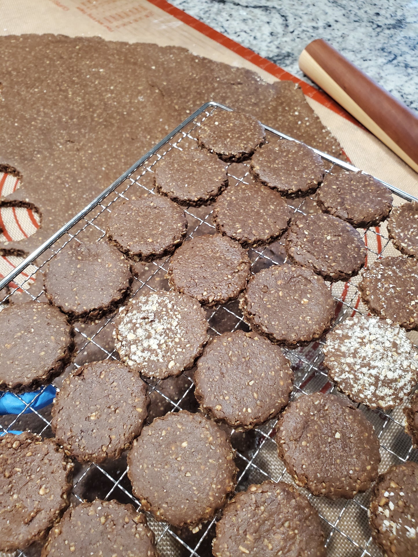 Baked treats on a cooling rack with a rolling pin and baking sheet in the background.