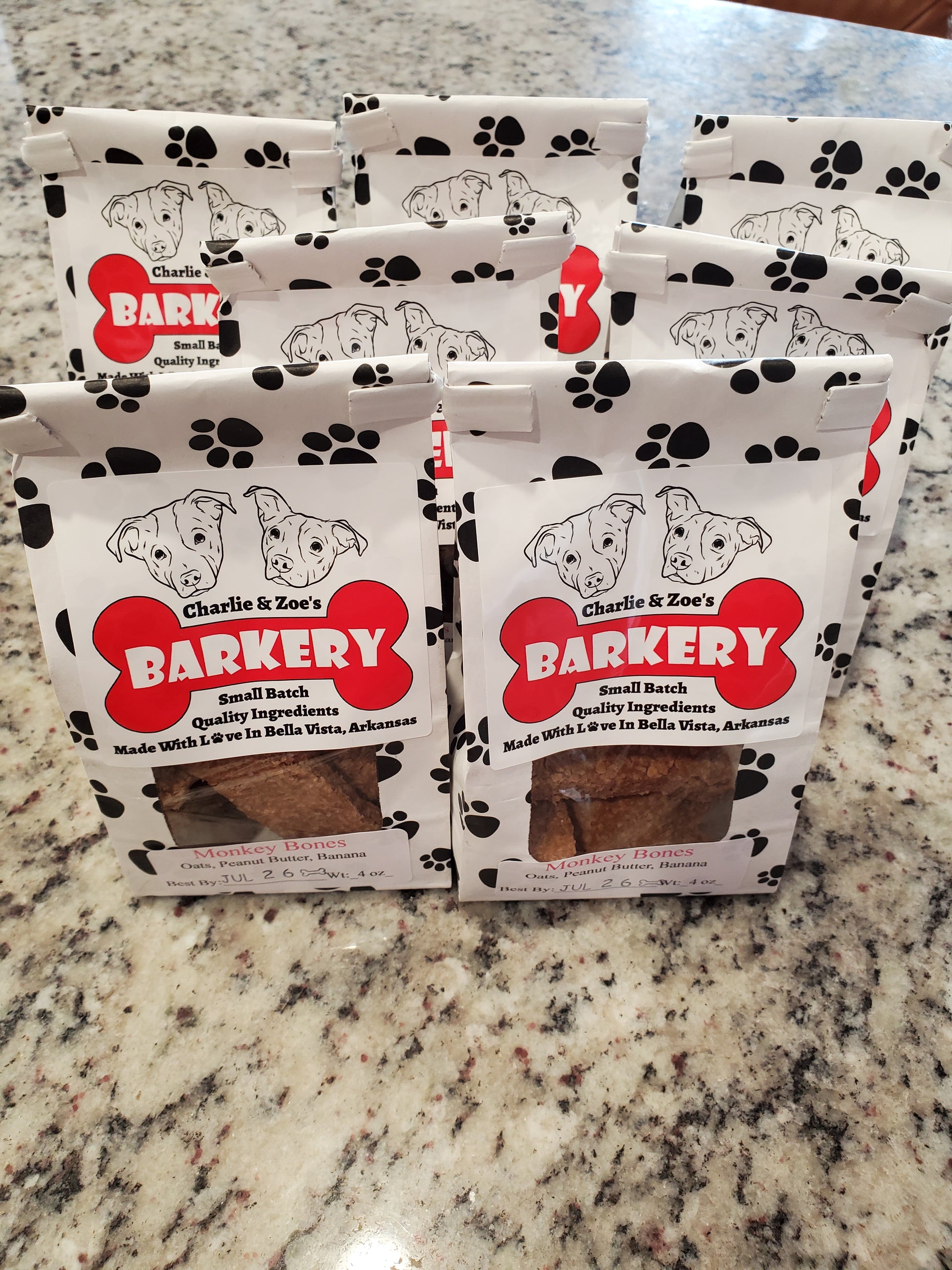 Four packages of Charlie & Zoe's Barkery dog treats on a granite countertop.