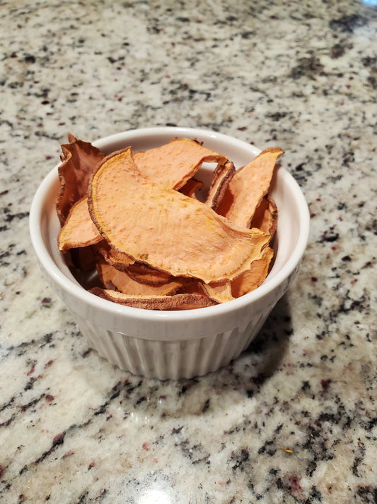 White bowl filled with sweet potato chips on a granite countertop